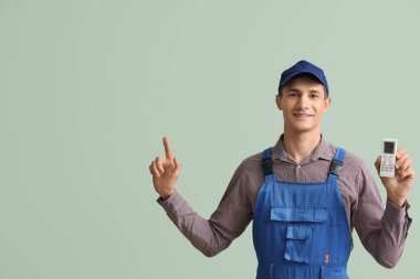 Klima uzaktan kumandalı erkek teknisyen yeşil arka plandaki bir şeyi işaret ediyor.