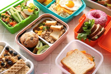 Bej kaplama arka planda farklı lezzetli yemekleri olan bir sürü beslenme çantası.