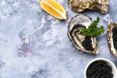 Lezzetli istiridyeler ve mavi arka planda siyah havyar.