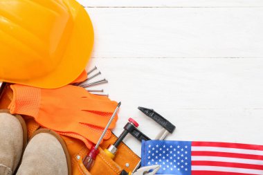 Koruyucu teçhizat, aletli kemer ve beyaz ahşap arka planda Amerikan bayrağı. İşçi Bayramı kutlamaları