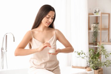 Banyoda bir kavanoz kremalı genç kadın.