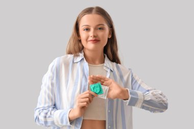 Ön planda prezervatifi olan genç bir kadın.