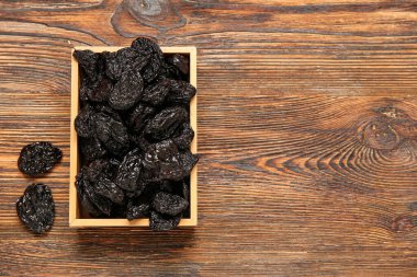 Ahşap zeminde lezzetli kurutulmuş eriklerle dolu bir kutu.