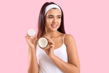 Pembe arka planda hindistan cevizi yağı olan güzel genç bir kadın.