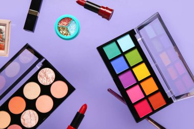 Leylak arka planında uçan dekoratif kozmetik ürünler