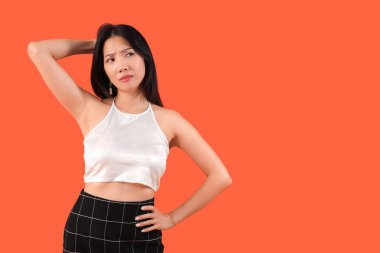 Turuncu arka planda düşünceli, güzel, Asyalı bir kadın.