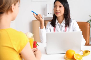 Laptop ve hasta ile çalışan Asyalı kadın beslenme uzmanı.