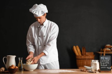 Siyah arka planda ham hamuru olan yakışıklı genç şef.