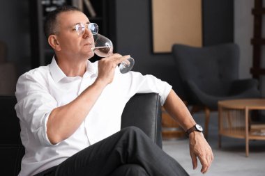 Yetişkin bir adam evde şarap tadıyor.