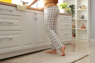 Hafif mutfakta, yumuşak halıda çıplak ayaklı kadın.