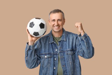 Kahverengi arka planda futbol topu olan mutlu ve olgun bir adam.