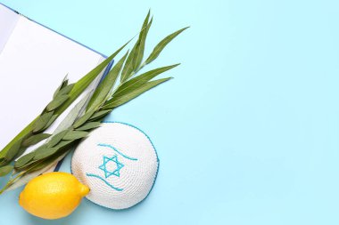 Dört tür (lulav, hadas, arava, etrog) Sukkot festival sembolleri, kippah ve mavi arkaplan üzerine açık kitap