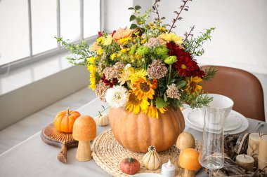 Şenlikli yemek masasında balkabağında güzel bir buket sonbahar çiçeği.