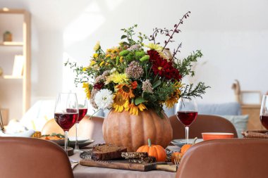 Şenlikli yemek masasında sonbahar çiçekli balkabağı, yakın plan.