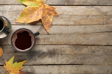 Ahşap arka planda bir fincan aromatik kahve ve sonbahar yapraklı kompozisyon