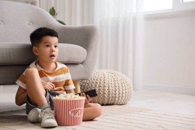 Patlamış mısırlı küçük Asyalı çocuk evde televizyon izliyor.