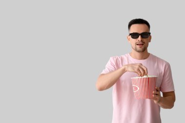 Üç boyutlu gözlüklü, patlamış mısırlı mutlu genç adam.