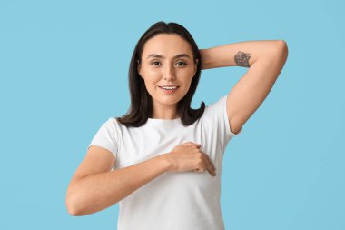 Mavi arka planda göğüslerini kontrol eden genç bir kadın. Kanser farkındalığı kavramı