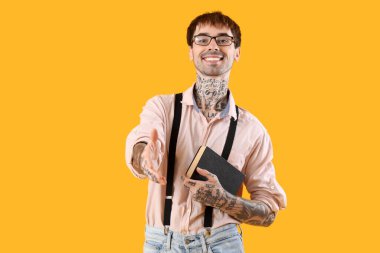 Sarı arka planda kitabı olan mutlu genç adam.