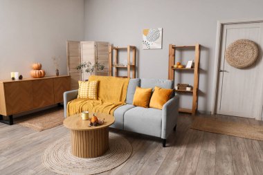 Kahve masasında gri kanepe ve balkabağı olan modern oturma odasının içinde.