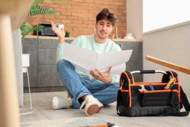 Mutfakta mobilya montajıyla kafası karışmış genç bir adam.