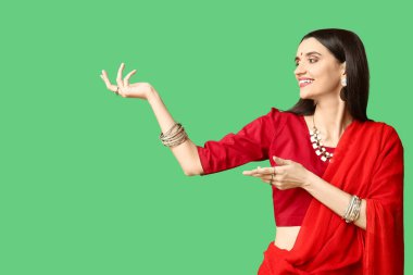 Sari giymiş, yeşil arka planda dans eden güzel bir Hintli kadın. Divaly kutlaması