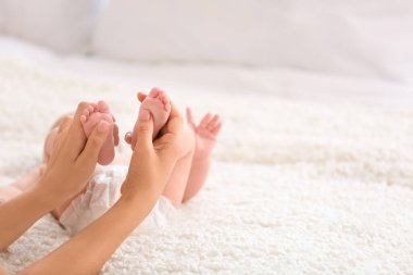 Mother massaging her baby's feet in bedroom, closeup