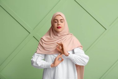 Yeşil arka planda meditasyon yapan tesettürlü güzel Müslüman kadın. Zen kavramı