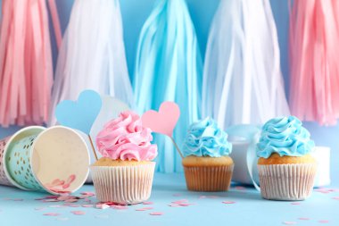 Hediye kutusu ve mavi arka planda süslemeleri olan lezzetli kekler. Cinsiyet ortaya çıkan parti kavramı