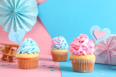 Hediye kutusu, süslemeleri ve renkli arka planda oyuncakları olan lezzetli kekler. Cinsiyet ortaya çıkan parti kavramı