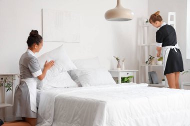 Otel odasında yatak yapan güzel oda hizmetçileri.