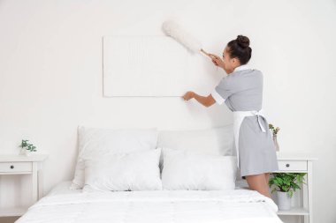 Güzel oda hizmetçisi, otel odasını temizliyor.