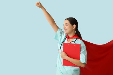 Mavi arka planda panosu olan süper kahraman kostümlü güzel bir kadın doktor.