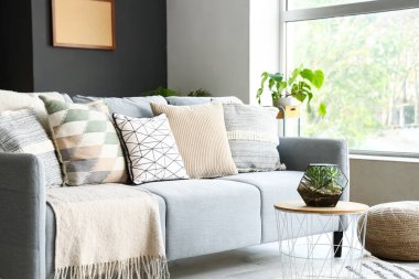 Modern oturma odasının içinde rahat gri kanepe ve kahve masasının üzerinde floraryum var.