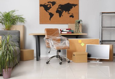 Taşındığı gün koltuğu streç film ve karton kutulara sarılı olan ofis.