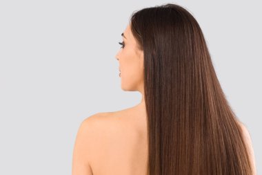 Genç, esmer, güzel saçlı, açık arka planda bir kadın.