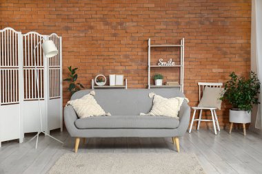 Modern oturma odasının içindeki yastıklı rahat gri kanepe.