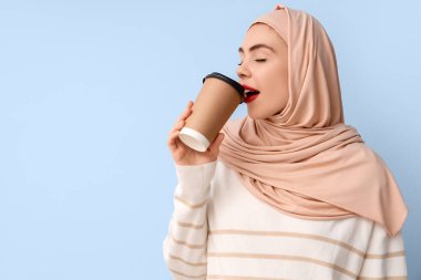 Mavi arka planda bir fincan kahvesi olan güzel Müslüman kadın.