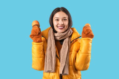 Mavi arka planda dekoratif mantarları olan sıcak eşarplı güzel Asyalı bir kadın.