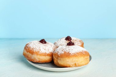 Hanuka kutlaması için lezzetli çöreklerle dolu tabaklar renk arka planına karşı aydınlık masada.
