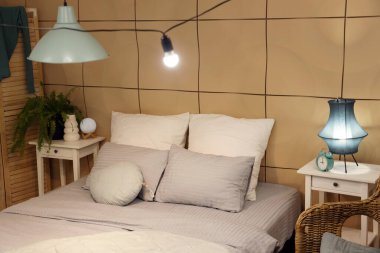 Parlayan lamba ve geceleri masaları olan şık bir yatak odası.