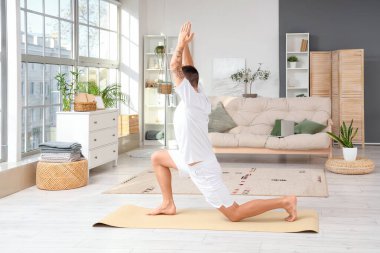 Evde yoga yapan genç bir adam.