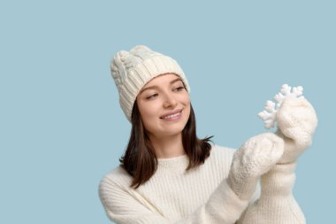 Mavi arka planda dekoratif kar taneleri olan güzel genç bir kadın.