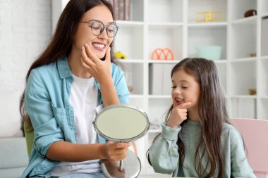 Aynalı bir Asyalı kadın konuşma terapisti ve ofiste mektupları telaffuz eden küçük bir kız.