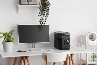 Modern bilgisayar ve taşınabilir güç istasyonu ile rahat çalışma alanı