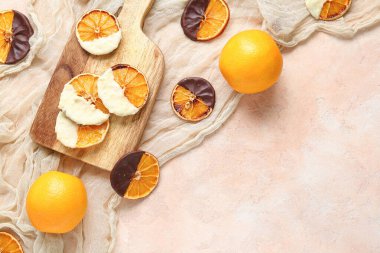 Bej arka planda çikolata soslu kurutulmuş portakal dilimleri olan ahşap tahta.