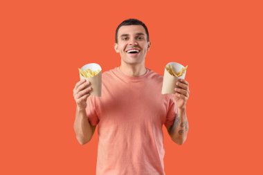 Turuncu arka planda patates kızartması olan mutlu genç adam.