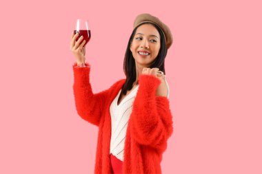 Pembe arka planda kırmızı şarap kadehi olan güzel Asyalı kadın.