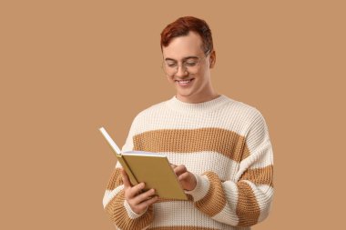 Gözlüklü genç adam renk arkaplanı kitabı okuyor.