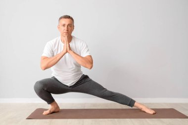Olgun adam ışık duvarının yanında yoga yapıyor.